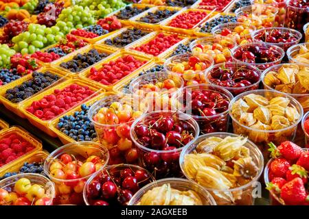 Frutta fresca al display sul mercato degli agricoltori in stallo.Rasbhari lampone, fragola, ciliegia, frutti di bosco e uva in contenitori di plastica. Foto Stock