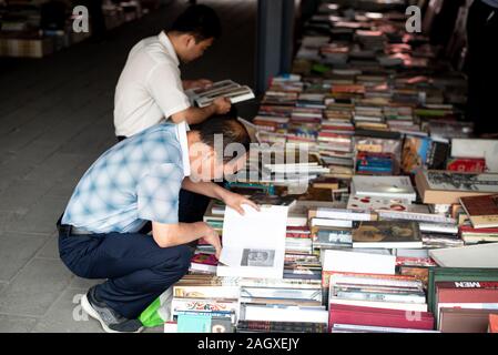 Pechino, Cina - 3 Giugno 2018: Cinese uomini asiatici la lettura di libri antichi a Panjiayuan pulci Mercato di antiquariato a Beijing in Cina. Foto Stock