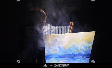 Artista copista paint seascape con nave in oceano. Fumo Vaper vape e-sigaretta. Artigiano arredatore disegnare come barca vela sul mare blu con colori acrilici. Foto Stock