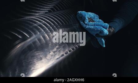 Utilizzando uno straccio nel palmo della tua mano, finitura auto liquido polacchi sono rimosse dall'auto. Strati di crema elimina dal corpo vettura. Processo di lucidatura delle auto. Foto Stock