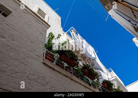 Vista panoramica, street view dalla splendida città di Locorotondo, provincia di Bari, Puglia Puglia , Italia Meridionale. White Servizio lavanderia Asciuga sul balcone bianco Foto Stock