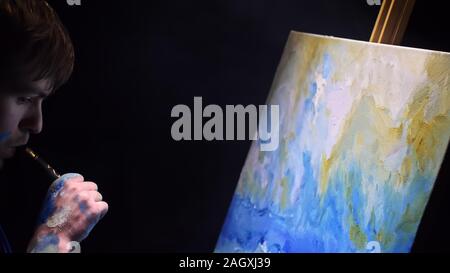 Artista copista paint seascape con nave in oceano. Fumo Vaper vape e-sigaretta. Artigiano arredatore disegnare come barca vela sul mare blu con colori acrilici. Foto Stock