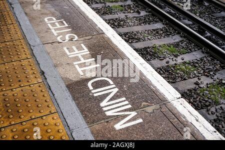 Mente la fase scritta sulla piattaforma del treno vicino a rotaie a Londra il DLR (Docklands Light Railway) dalla stazione Foto Stock