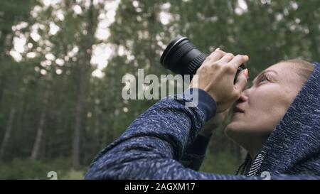 Traveler fotografare la vista panoramica nella foresta. Una donna caucasica riprese close up look. Ragazza scatta foto video su mirrorless reflex fotocamera. Foto Stock