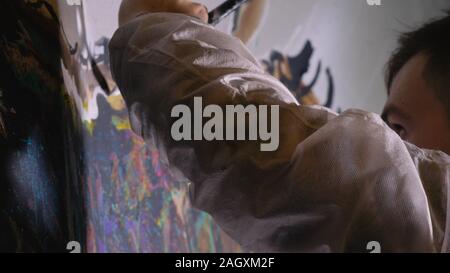 Artista designer disegna un aquila sulla parete. Artigiano vernici di decoratore foto con olio acrilico colore. Pittore pittore vestito in cappotto di vernice. Indoor. Foto Stock