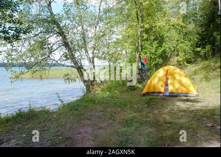 Tenda gialla sulla riva del lago, tenda turistico sulle rive del laghetto Foto Stock