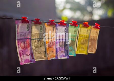 Messa a fuoco selettiva di nuovo la valuta indiana constata rupie dieci,venti,cinquanta cent,duecento,cinquecento e due mila appeso a un filo. Foto Stock