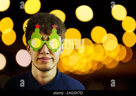 Ritratto di un uomo in bicchieri di Natale. Foto di sorridere da stupidi ragazzo con gli occhiali di natale. Copia spazio per il testo. Foto Stock