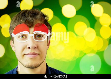 Ritratto di un uomo in bicchieri di Natale. Ritratto di un uomo in bicchieri di Natale. Foto di sorridere da stupidi ragazzo con gli occhiali di natale. Copia spazio per il testo Foto Stock