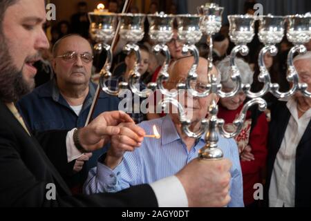 Bremen, Germania. 22 Dic, 2019. Rabbi Natanel Teitelbaum (l) accende un cero Hanukkah insieme con superstite dell' Olocausto Grigori Skoblov (90) all'Hanukkah celebrazione nella Comunità Ebraica centro a Brema in occasione del 'International superstiti notte' del popolo ebraico rivendicazioni da conferenza. La cerimonia in onore dei sopravvissuti all Olocausto avrà luogo anche a Monaco di Baviera, New York, Mosca, Parigi e Gerusalemme. Credito: Jörg Sarbach/dpa/Alamy Live News Foto Stock