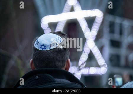 Bremen, Germania. 22 Dic, 2019. In occasione del "International superstiti notte' delle rivendicazioni ebraica Conferenza per l'Hanukkah celebrazione davanti al Jewish Community Center di un giovane ebreo sorge nella parte anteriore di un illuminato Stella di Davide. La cerimonia in onore dei sopravvissuti all Olocausto avrà luogo anche a Monaco di Baviera, New York, Mosca, Parigi e Gerusalemme. Credito: Jörg Sarbach/dpa/Alamy Live News Foto Stock