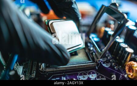 Ingegnere repairman tenendo le mani in guanti neri chip processore, CPU da inserire nella presa della scheda madre del computer. Il concetto di tecnologia Foto Stock