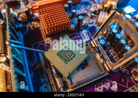 Moderno processore CPU sulla scheda madre del computer. Il concetto di tecnologia hardware e riparazione nella luce al neon Foto Stock