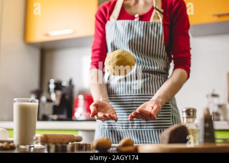 Cuocere casalinga rendendo i cookie a casa su una cucina colorata. La donna getta la pasta fino a tavola con ingredienti Foto Stock