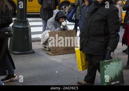 Sconsolato senzatetto US marina il veterano raggiunge fuori come acquirenti e turisti passano lungo la Quinta Avenue nel centro di Manhattan su 'Venerdì Nero" Foto Stock