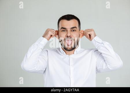 Ritratto di divertenti uomo barbuto ingannare circa su sfondo grigio. Foto Stock