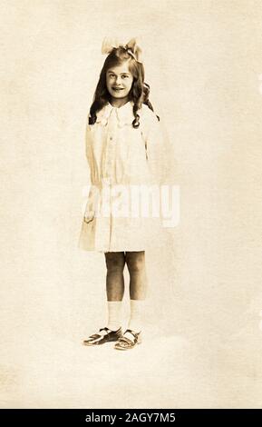 Ritratto a figura intera di una bambina intorno all età di dieci anni in piedi per la sua fotografia, circa 1915. Foto Stock