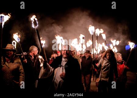 East Hoathly, UK. 22 dicembre, 2019. Gli abitanti di un villaggio di lavorazione a lume di torcia dal Kings Head pub A Christmas Carol service presso east hoathly chiesa in East Sussex, Regno Unito. La figura mostra il Reverendo Phil Hodgins portando la processione. Credito: Jim Holden/Alamy Live News Foto Stock