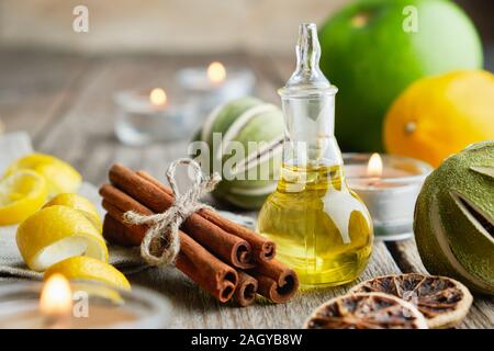 Bottiglia di agrumi Olio essenziale di limone per aromaterapia, agrumi, bastoncini di cannella e candele accese. Foto Stock
