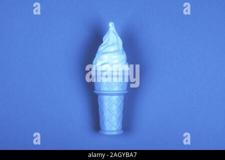 Una cremosa di gelati con il cono virati al trendy classico sfondo blu. Colore trend di concetto 2020. Foto Stock