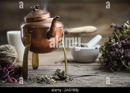 Antica teiera in ebollizione, mortaio coneflowers secco e il mazzetto di timo. Foto Stock