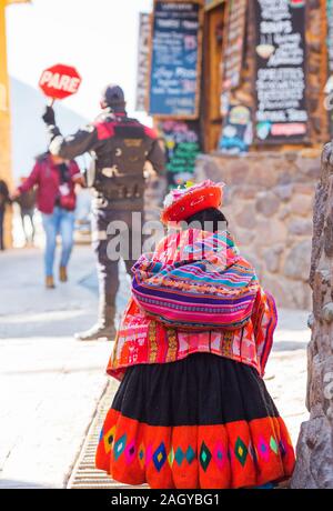 OLLANTAYTAMBO, Perù - Giugno 26, 2019: Donna Peruviana cholita vestito nel tradizionale tessuto colorato. Vista posteriore. In verticale Foto Stock