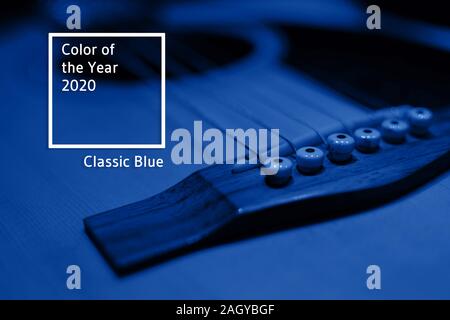 Frammento di corpo e stringhe di un classico chitarra acustica in una stanza buia sotto la luce blu. Selective soft focus. Principale tendenza colore del 2020. Foto Stock