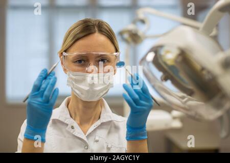 Dentista femmina in bicchieri e una Benda di garza in uno studio dentistico. Foto Stock