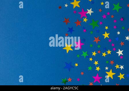 Coriandoli multicolori stelle sul classico sfondo blu il minimo concetto creativo. Spazio per la copia. Foto Stock