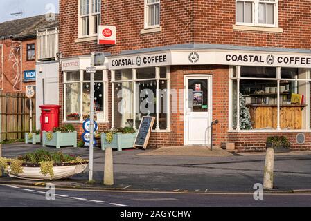 Coastal Coffee shop a West Mersea, Mersea Island, Essex, UK con Post Office. Barca a remi piantati con impianti al di fuori della decorazione Foto Stock