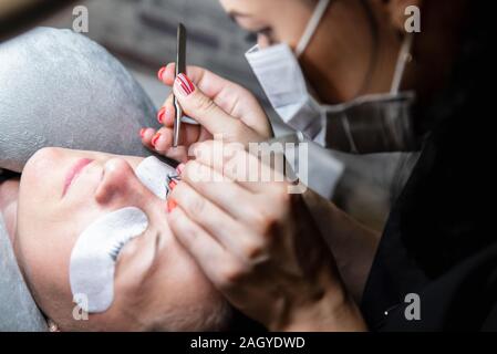 Impilatura di ciglia. Processo di estensioni di ciglia nel salone di bellezza. Tema di bellezza e di cura per se stessi Foto Stock