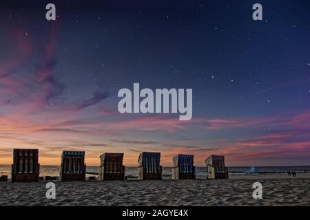Linea di sedi di sole sulla spiaggia del Mar Baltico quando il giorno incontra la notte e stelle appaiono Foto Stock