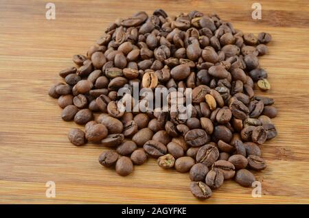 Cumulo di chicchi di caffè sul bambù superficie in legno Foto Stock