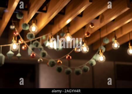 Sfondo sfocato, texture. Ghirlande di natale di sfere luminose, forme geometriche e lampade retrò. Decorazioni di festa di lampade e giocattoli di Natale per Chris Foto Stock