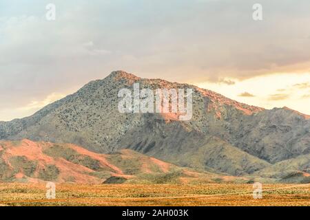 Le linee di alimentazione si dipanano attraverso montuoso il paesaggio del deserto al tramonto, Deserto Mojave, CALIFORNIA, STATI UNITI D'AMERICA Foto Stock