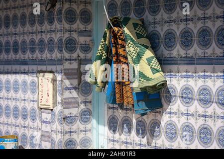 I tappetini di preghiera si asciugano al sole fuori della casa blu delle piastrelle a Hergla, Tunisia Foto Stock