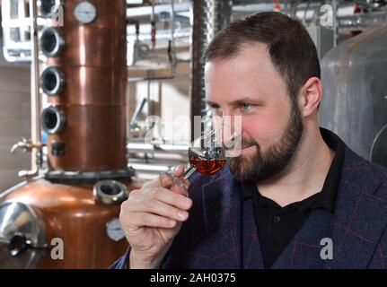 16 dicembre 2019, Sassonia-Anhalt, Zeitz: Daniel Rost, mastro distillatore e proprietario dell'impresa Zeitzer Whisky fabbricazione; prove un whisky. Circa 22000 litri di alcole puro brucia la ruggine per anno a Zeitz. Nuovo barili vengono aggiunti regolarmente al magazzino e un massimo di un barile al mese viene imbottigliato. In questo momento i tre e i cinque anni di whisky è disponibile. La domanda è aumentata significativamente prima di Natale, dice il chimico addestrato. Secondo l'Associazione tedesca delle distillerie di whisky, la quota di mercato di lingua tedesca il whisky è 0,4%. Ci sono attualmente 210 distillerie di whisky in Germania Foto Stock