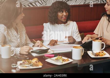 Multi-etnico team business avente il pranzo al cafe e discutere idee e progetti Foto Stock