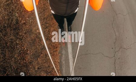 La formazione di un atleta sul rullo pattinatori. Il biathlon ride sul rullo di sci con bastoncini da sci, nel casco. Pov azione di visualizzazione cam.Autunno allenamento. Il rullo Foto Stock