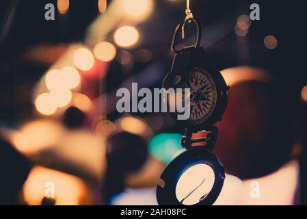 Bellissimo bokeh di fondo di una bussola appeso con luci e riflessioni in background. Concetto di essere perduti, libertà e ricerca della felicità. Foto Stock