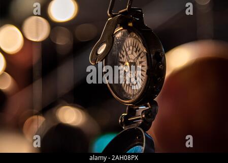 Bellissimo bokeh di fondo di una bussola appeso con luci e riflessioni in background. Concetto di essere perduti, libertà e ricerca della felicità. Foto Stock