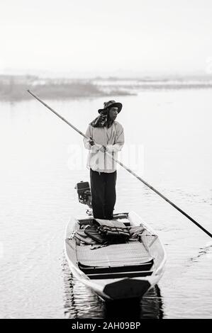 JAN 13, 2019 Udonthani, Thailandia - pescatore o asiatiche locali pilota di barca con la barca di legno nel tranquillo lago di Nong Harn nel quartiere Kumphawapi Foto Stock