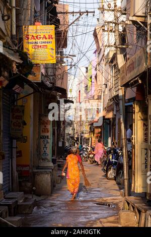 Vista posteriore del senior donna in sari tenendo la scopa mentre si cammina in vicolo, Trichy, Tamil Nadu, India Foto Stock