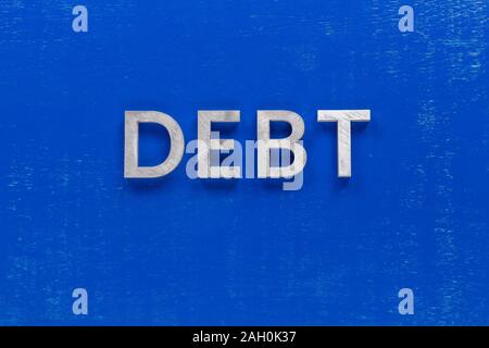 la parola debito pagato su tavola dipinta blu con spessore caratteri abcape in metallo argento Foto Stock