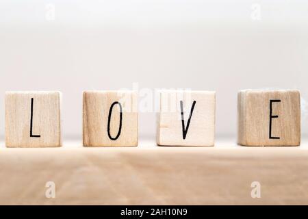 La parola amore su cubi di legno con cuore rosso, close-up vicino a sfondo bianco Foto Stock