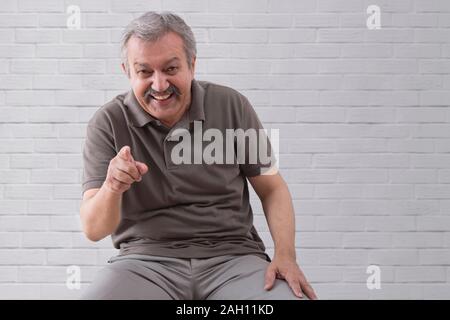 Ritratto di un felice uomo senior di ridere e di puntare il dito. Foto Stock