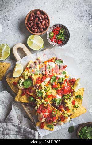 Nachos chips con salsa al formaggio, guacomole, salsa e verdure sulla scheda. Parte il concetto di cibo. Cibo messicano concetto. Foto Stock