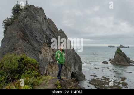 La donna sta di fronte al litorale roccioso su Nuvoloso Giorno Foto Stock