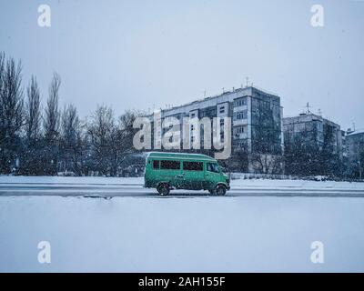 Autobus a una brutta strada d'inverno. Lonely autobus verde sulla piccola strada in inverno città Foto Stock