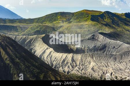 Vista ravvicinata del Monte Bromo cratere in primo piano e il verde delle colline in lontananza durante un bellissimo tramonto. Foto Stock